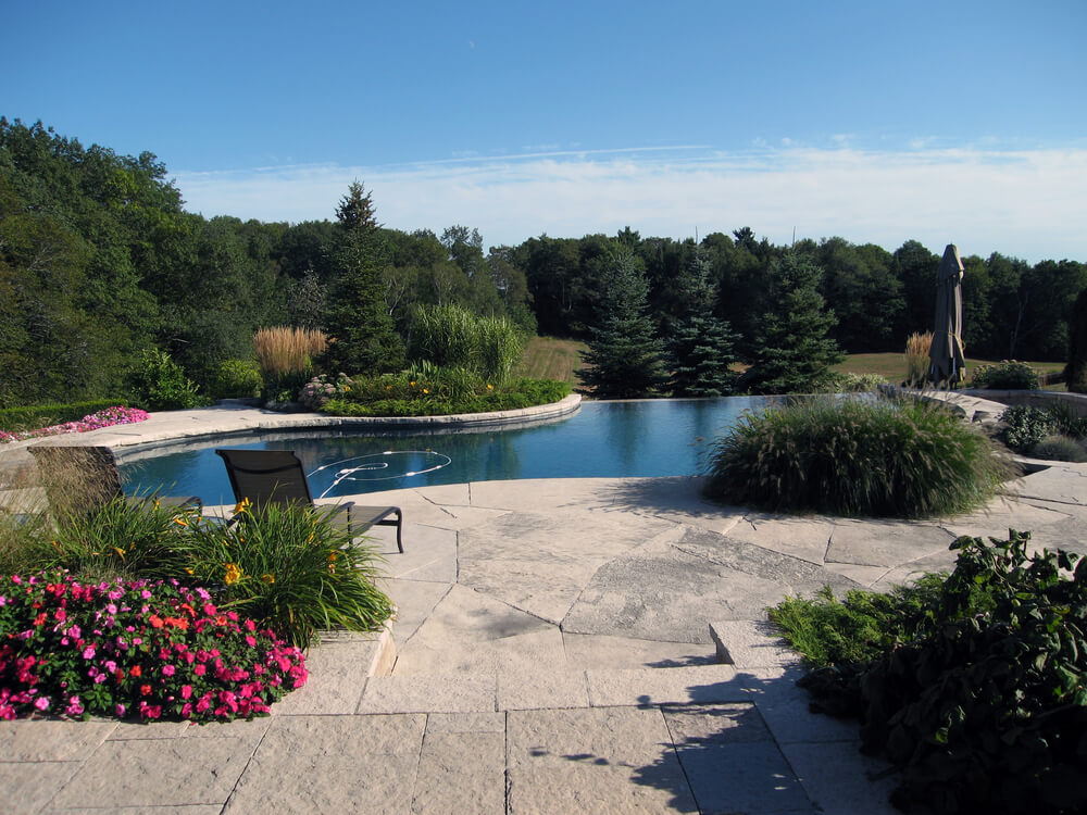 Large dark blue infinity pool overlooking meadow and forest. Large dark blue infinity pool overlooking meadow and forest.