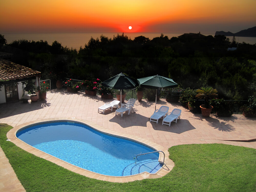Pool and patio in small backyard of a home high up on a hill overlooking forest and ocean with spectacular sunset. Pool and patio in small backyard of a home high up on a hill overlooking forest and ocean with spectacular sunset.