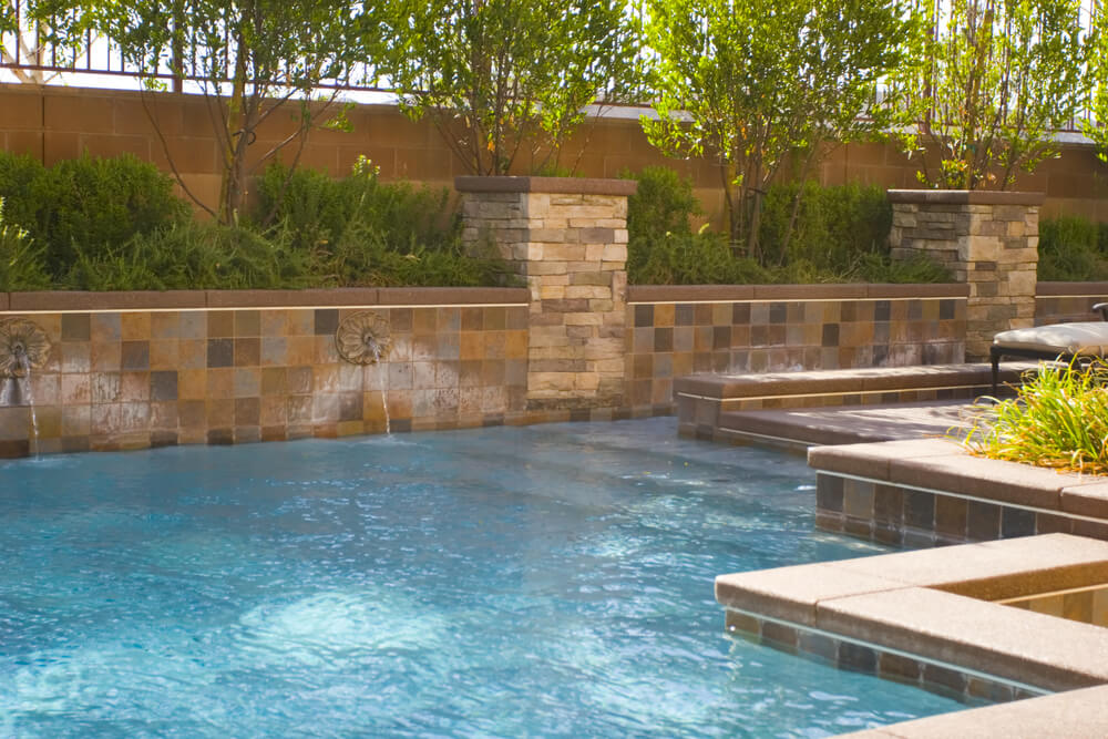Close up of pool with brick fence and tree hedge. Close up of pool with brick fence and tree hedge.