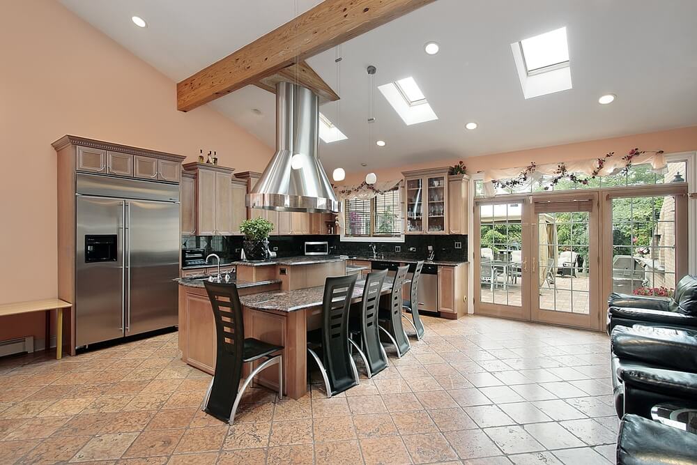 This kitchen features a bright mixture of modern and traditional looks, with exposed beams and cabinets in natural wood, while space age metal chairs and stove hood reflect the aluminum appliances. This kitchen features a bright mixture of modern and traditional looks, with exposed beams and cabinets in natural wood, while space age metal chairs and stove hood reflect the aluminum appliances.