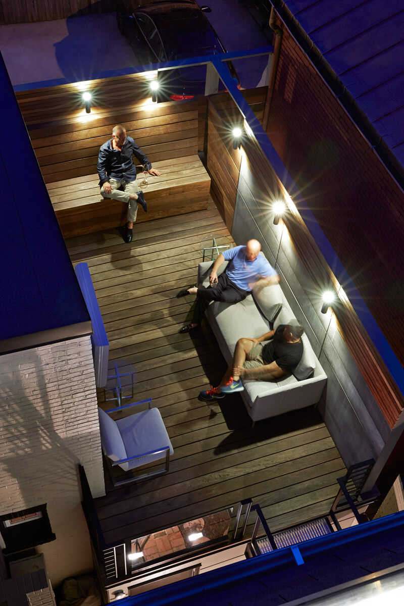 Overhead view of the upper deck, extending from the kitchen doorway onto the adjacent roof. This area features natural wood and sculpted metal, with bright sconce lighting all around. Overhead view of the upper deck, extending from the kitchen doorway onto the adjacent roof. This area features natural wood and sculpted metal, with bright sconce lighting all around.
