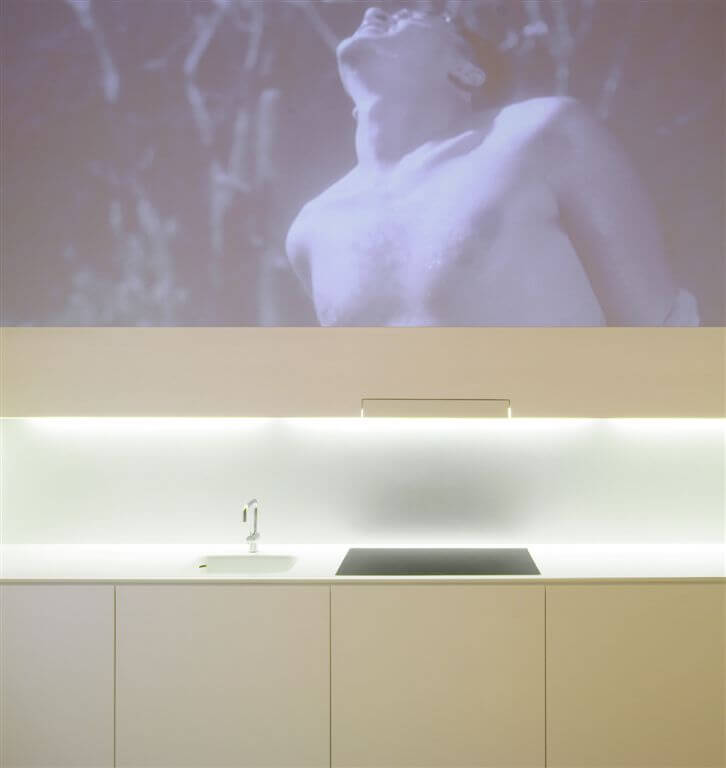 Close up shot of the kitchen sink and range area, highlighting minimalist design, projection area, and hidden cabinetry. Close up shot of the kitchen sink and range area, highlighting minimalist design, projection area, and hidden cabinetry.