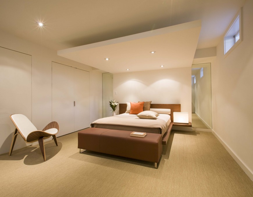 Wider view of same bedroom, showcasing unique folded wood chair and upper ground-level window. Wider view of same bedroom, showcasing unique folded wood chair and upper ground-level window.