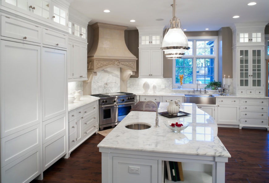 The large island with white marble countertop is the centerpiece in this expansive kitchen, flush