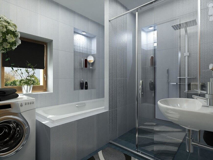 This bathroom shares a space with a washer and dryer, but there is still plenty of room to move around comfortably. Large grey tiles cover the walls and create a futuristic feel for the room. Notice the corner of a stylish carpet covering the floor. The bath and shower are taking up a large space, but their positioning helps to conserve area in the bathroom. This bathroom shares a space with a washer and dryer, but there is still plenty of room to move around comfortably. Large grey tiles cover the walls and create a futuristic feel for the room. Notice the corner of a stylish carpet covering the floor. The bath and shower are taking up a large space, but their positioning helps to conserve area in the bathroom.