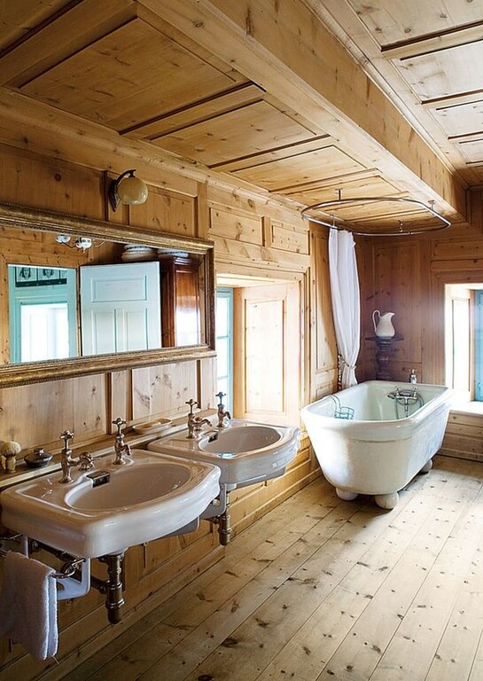 Natural wood fills this bathroom, covering the floor, the walls, and the ceiling. A clawfoot tub is featured in the corner between two windows. Directly to the left of the tub and window are two floating sinks sharing one large mirror. Natural wood fills this bathroom, covering the floor, the walls, and the ceiling. A clawfoot tub is featured in the corner between two windows. Directly to the left of the tub and window are two floating sinks sharing one large mirror.
