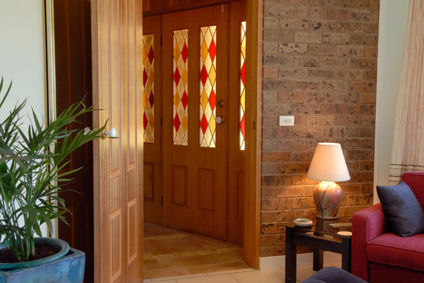 This entryway features rich stained wood doors, transitioning to red brick around the corner. The stained glass panels on the door maintain a low light in the entryway, and compliment the rich wood tones. This entryway features rich stained wood doors, transitioning to red brick around the corner. The stained glass panels on the door maintain a low light in the entryway, and compliment the rich wood tones.