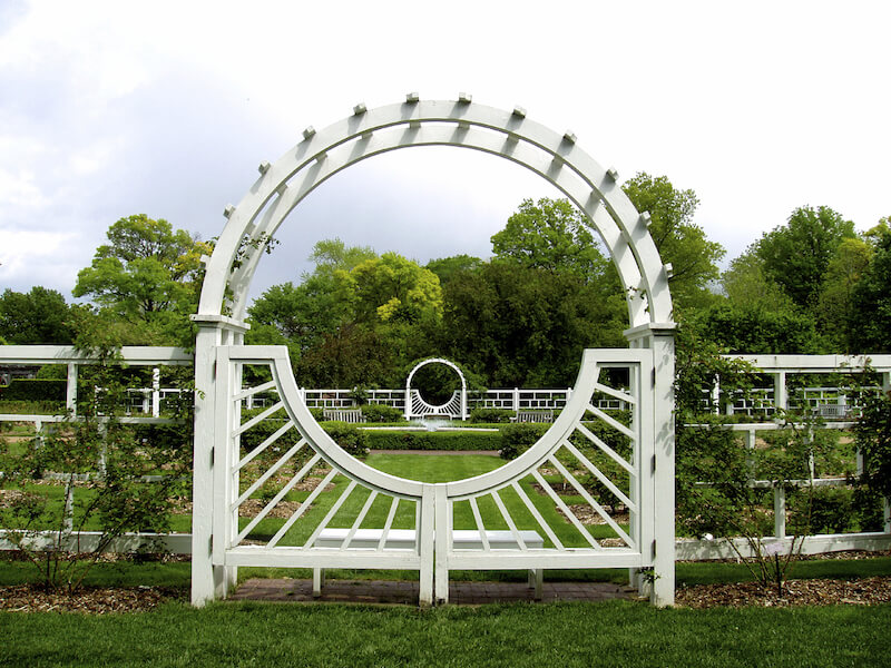 a thick white wooden arbor with a single gate attached to a modern style decorative fence - Arbor Designs Ideas a thick white wooden arbor with a single gate attached to a modern style decorative fence - Arbor Designs Ideas