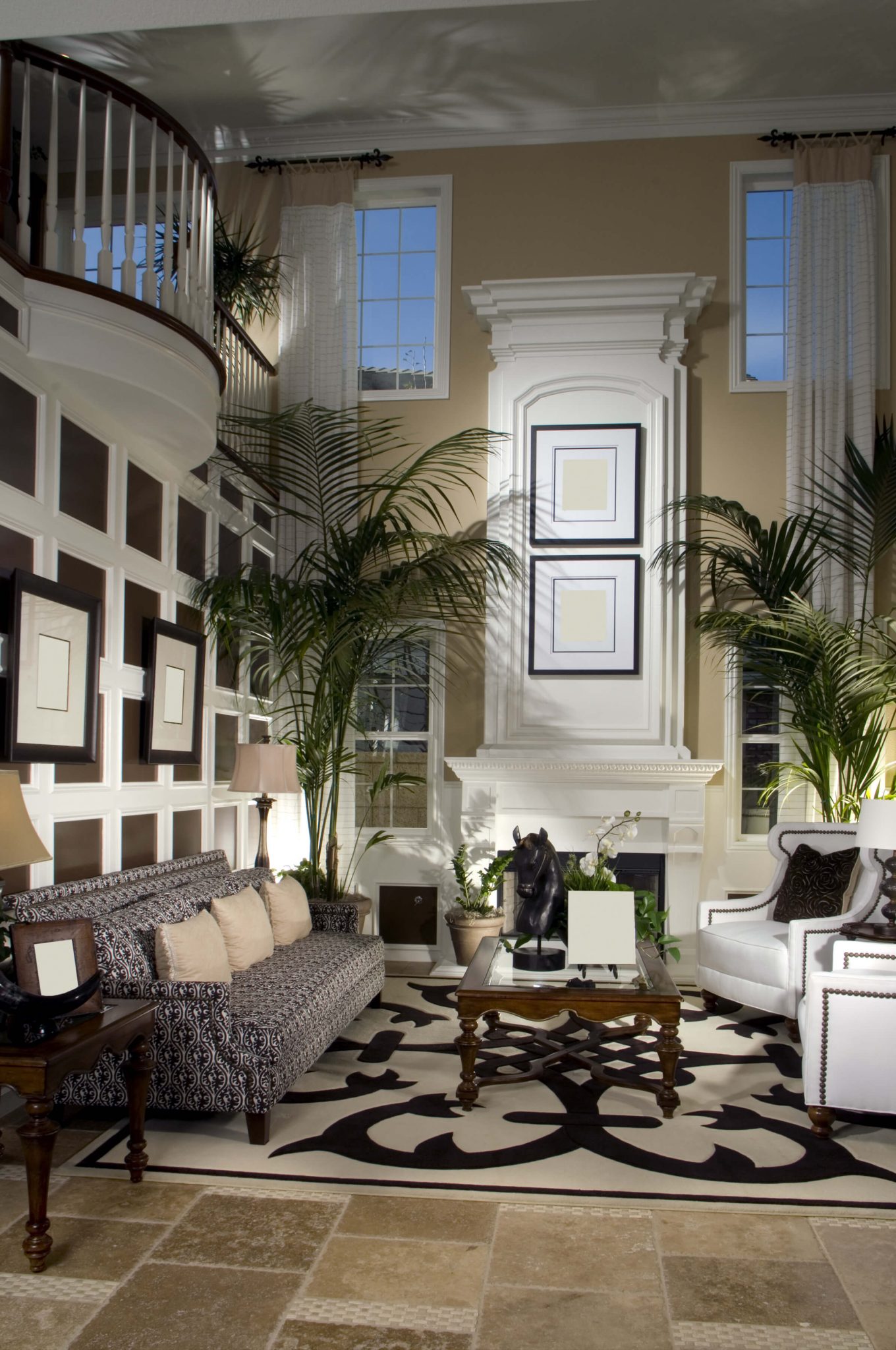 2 story great room with white fireplace, mezzanine looking down on living room, large rug and elegant dining room furniture (I particularly like the white armchairs).