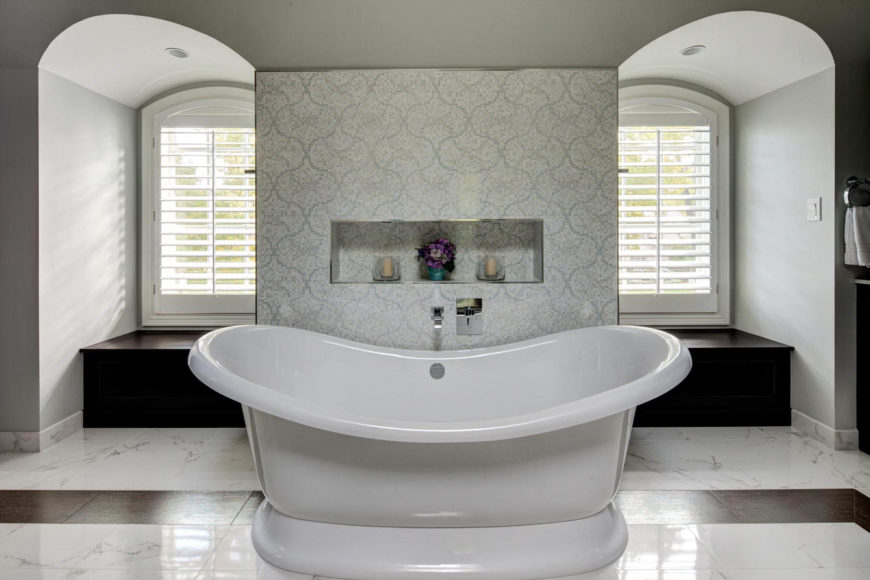 The free standing soaking tub commands attention at the center, before a patterned tile wall flanked by a pair of bay windows with storage beneath. The free standing soaking tub commands attention at the center, before a patterned tile wall flanked by a pair of bay windows with storage beneath.