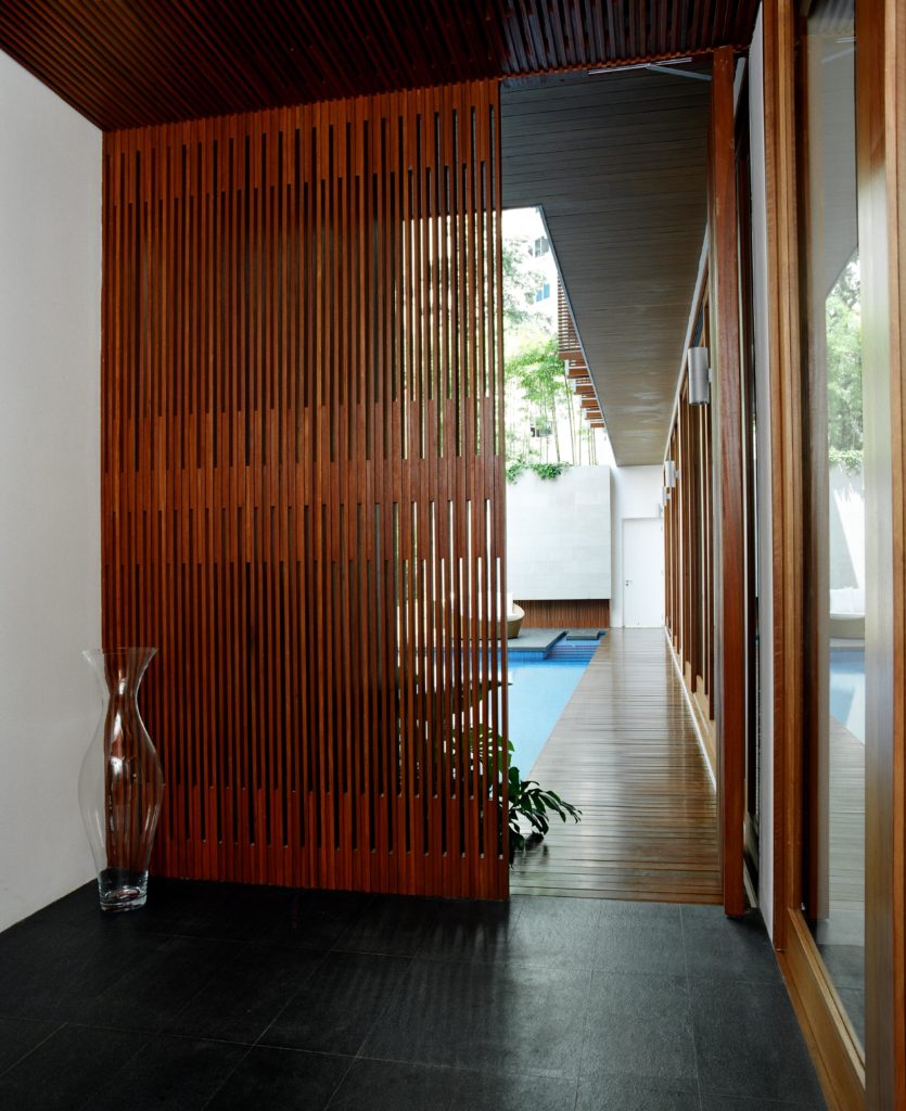 Entering the home over this black tile floor, through rich wood shades we see the inner courtyard pool area, with main living room on right behind full height glass panels. Entering the home over this black tile floor, through rich wood shades we see the inner courtyard pool area, with main living room on right behind full height glass panels.