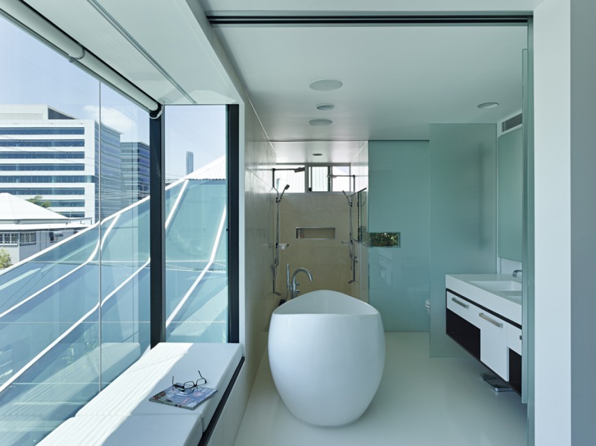 Bathroom features unique egg-shaped pedestal tub surrounded by layers of smoked glass. Window seating on white cushions at left, with walk in shower in background. Bathroom features unique egg-shaped pedestal tub surrounded by layers of smoked glass. Window seating on white cushions at left, with walk in shower in background.