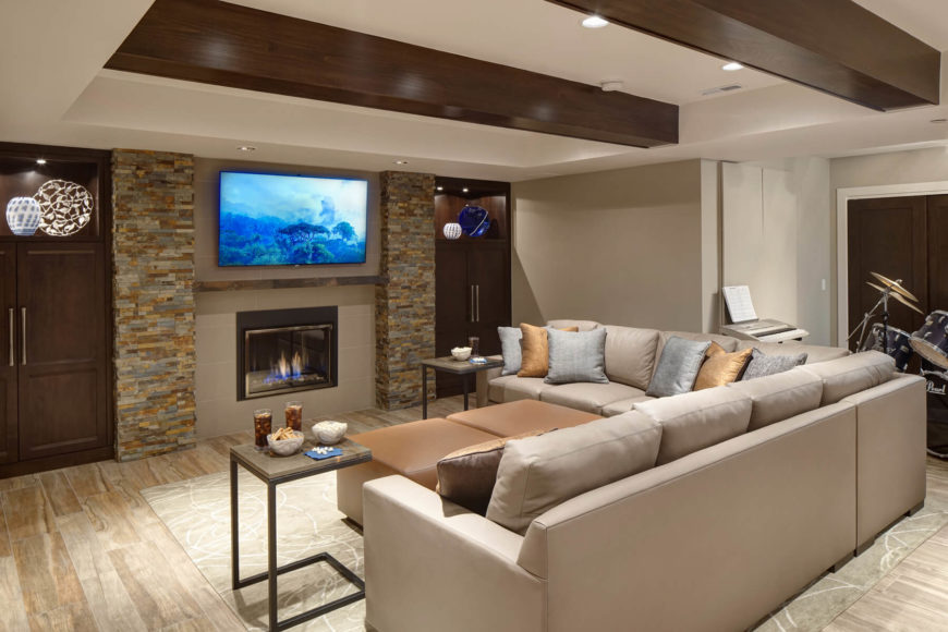 Massive L-shaped sectional defines this relaxing space, with a pair of light brown cubic ottomans at center. The porcelain plank floor tiling can be seen throughout, with its white-washed hardwood look. Exposed maple beams overhead aid in the rustic feel. Massive L-shaped sectional defines this relaxing space, with a pair of light brown cubic ottomans at center. The porcelain plank floor tiling can be seen throughout, with its white-washed hardwood look. Exposed maple beams overhead aid in the rustic feel.