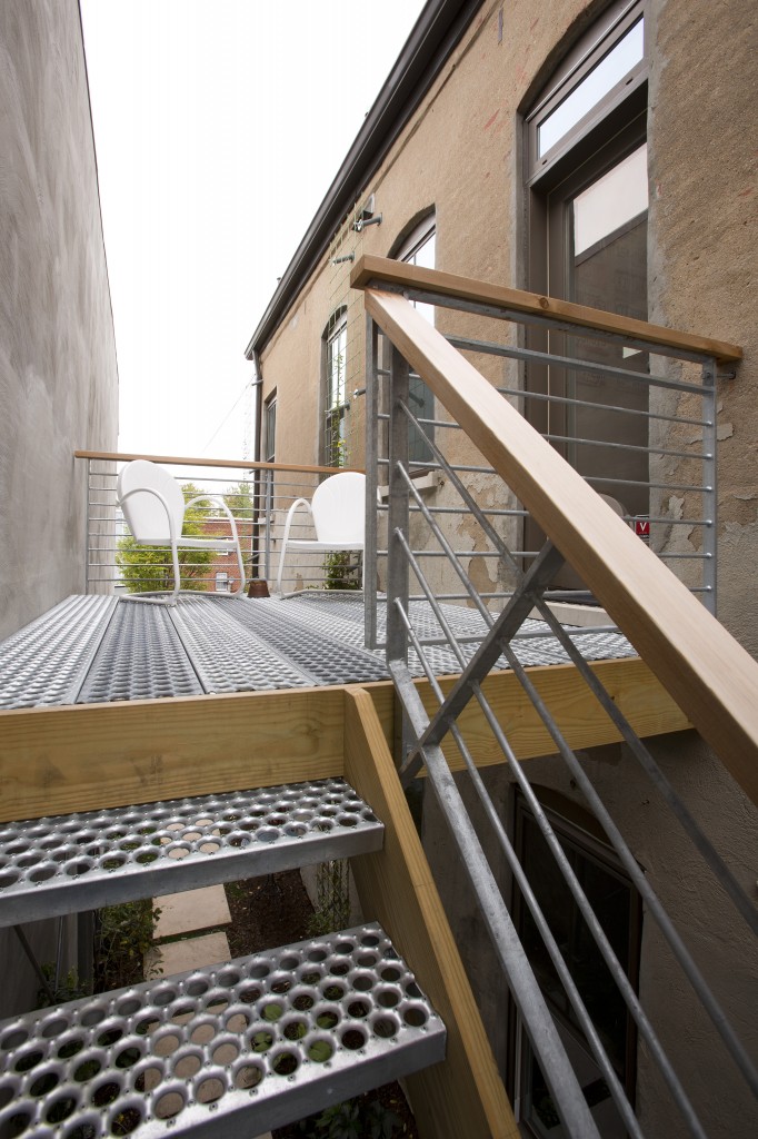 A landing coming off the back of the unit employs industrial-style stairs down to a garden walkway to the backyard. A landing coming off the back of the unit employs industrial-style stairs down to a garden walkway to the backyard.