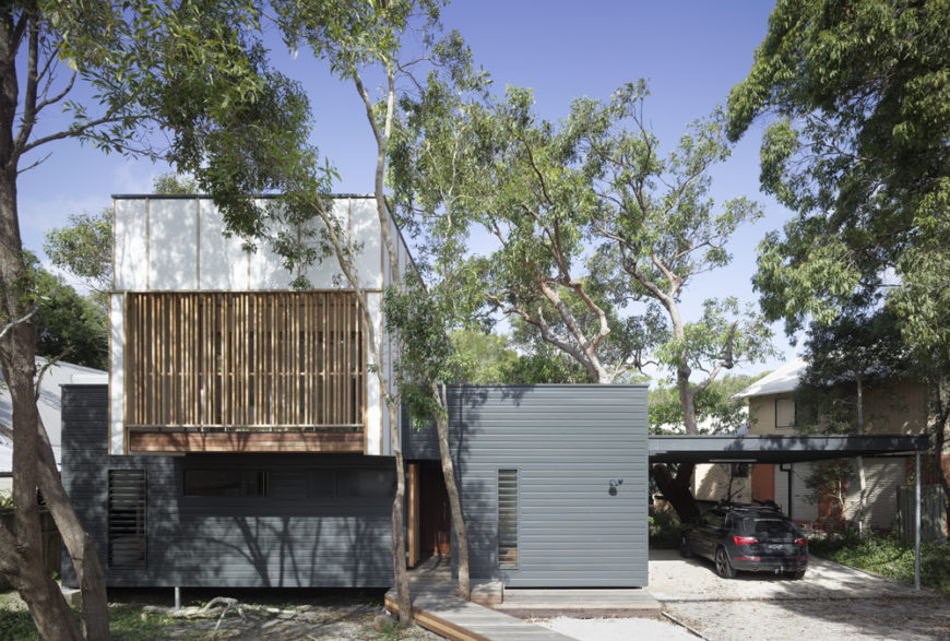 Seen from the street side, this minimalistic home obscures its striking design by hiding within the foliage, boasting a mixture of natural materials across the facade. Seen from the street side, this minimalistic home obscures its striking design by hiding within the foliage, boasting a mixture of natural materials across the facade.