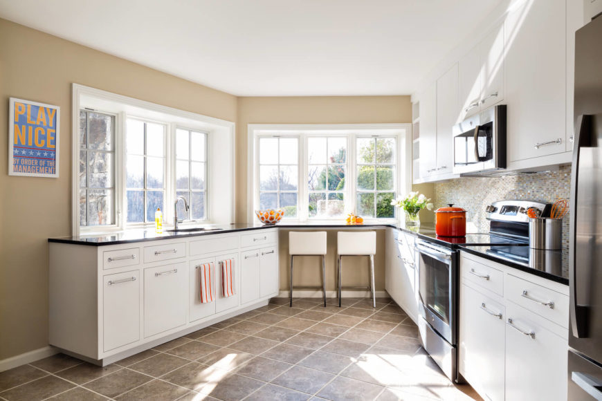 The airy kitchen is situated in an interesting section of the home that narrows towards the eat-in bar, taking the "kitchen triangle" to a whole new level. The high end appliances and white cabinets give this kitchen a bright, shiny, feeling of perfection. The airy kitchen is situated in an interesting section of the home that narrows towards the eat-in bar, taking the "kitchen triangle" to a whole new level. The high end appliances and white cabinets give this kitchen a bright, shiny, feeling of perfection.