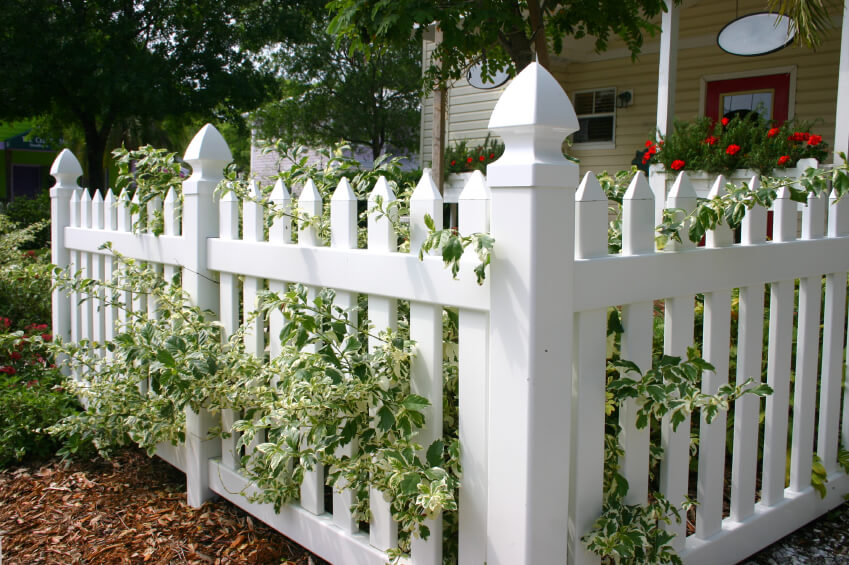 vinyl white picket fence in front of a small cottage with white 