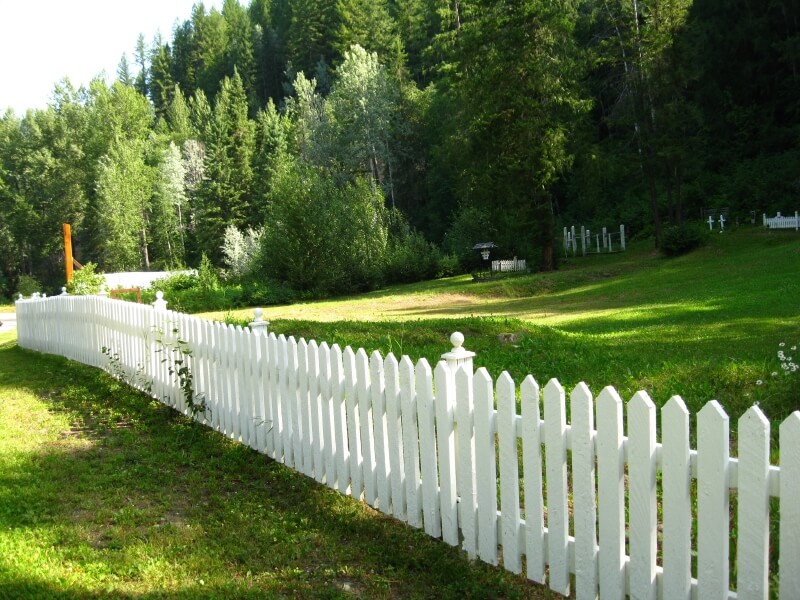 A picket fence serving as a perimeter of a graveyard in the countryside. A picket fence serving as a perimeter of a graveyard in the countryside.
