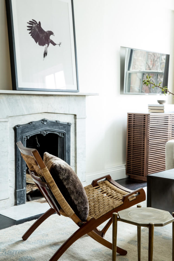 The open-plan living room includes interesting furniture pieces, like this folding wood and wicker chair, and the slatted wood media cabinet at right. The open-plan living room includes interesting furniture pieces, like this folding wood and wicker chair, and the slatted wood media cabinet at right.