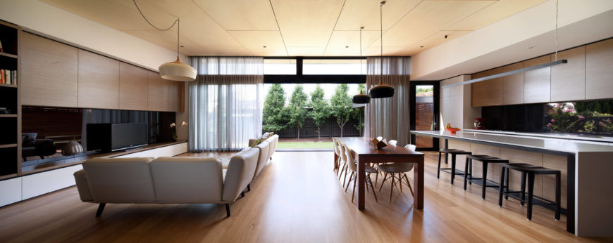 This panoramic view of the living room strikes a balance with its uniformity. The prolonged furniture--the L-shaped couch, the dining table and bar seating--maintain a prolonged effect, lending the an open feel to this room. This panoramic view of the living room strikes a balance with its uniformity. The prolonged furniture--the L-shaped couch, the dining table and bar seating--maintain a prolonged effect, lending the an open feel to this room.