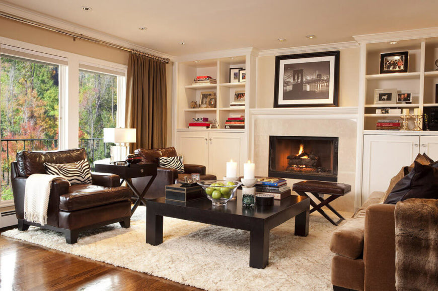 Turning the opposite direction in this large open space, we see a second full set of furniture revolving around a large dark wood coffee table and marble wrapped fireplace. The full height windows let daylight pour into the brightly hued space. Turning the opposite direction in this large open space, we see a second full set of furniture revolving around a large dark wood coffee table and marble wrapped fireplace. The full height windows let daylight pour into the brightly hued space.