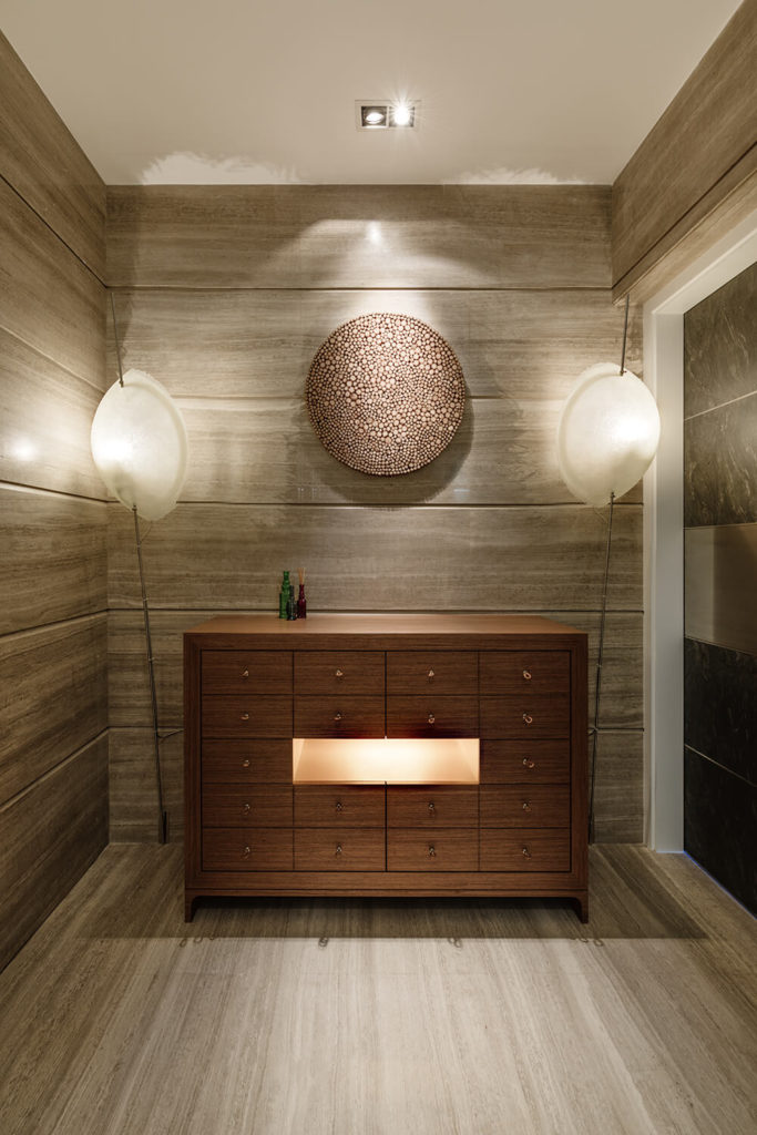 The foyer features stone walls and flooring, meant to mimic layers of sedimentary rock, an eye-catching piece of wall art, and lamps by Catellani & Smith designed to cast natural-looking shadows. The foyer features stone walls and flooring, meant to mimic layers of sedimentary rock, an eye-catching piece of wall art, and lamps by Catellani & Smith designed to cast natural-looking shadows.