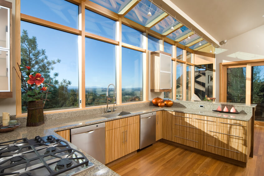 The vast array of large windows creeping up to the ceiling overhang illuminate this kitchen with ample sunlight. The granite countertops wrap over natural wood cabinetry, with rich hardwood flooring connecting the expanse. You'll notice that even the large windows and doors are framed in a light natural wood. The vast array of large windows creeping up to the ceiling overhang illuminate this kitchen with ample sunlight. The granite countertops wrap over natural wood cabinetry, with rich hardwood flooring connecting the expanse. You'll notice that even the large windows and doors are framed in a light natural wood.