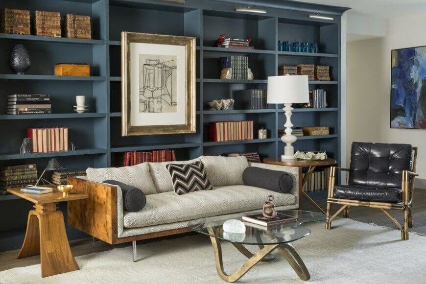 For owners with a smaller collection, arranging like items together with knick-knacks and accent pieces is a great way to fill the vertical space. This design also attaches a large piece of artwork to the empty shelves just above the sofa.