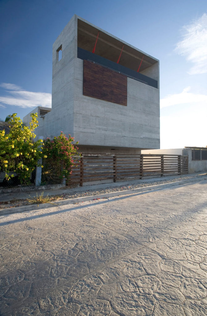 Here is a street view of the house, the exclusion of a traditional front door is due to the decision to construct the house out of concrete. Cutting a hole for a door would have been a compromise of tectonic support. This also forces any guests to the house to walk around the side to the back and get a full view of the structure and surrounding tropical vegetation. Here is a street view of the house, the exclusion of a traditional front door is due to the decision to construct the house out of concrete. Cutting a hole for a door would have been a compromise of tectonic support. This also forces any guests to the house to walk around the side to the back and get a full view of the structure and surrounding tropical vegetation.