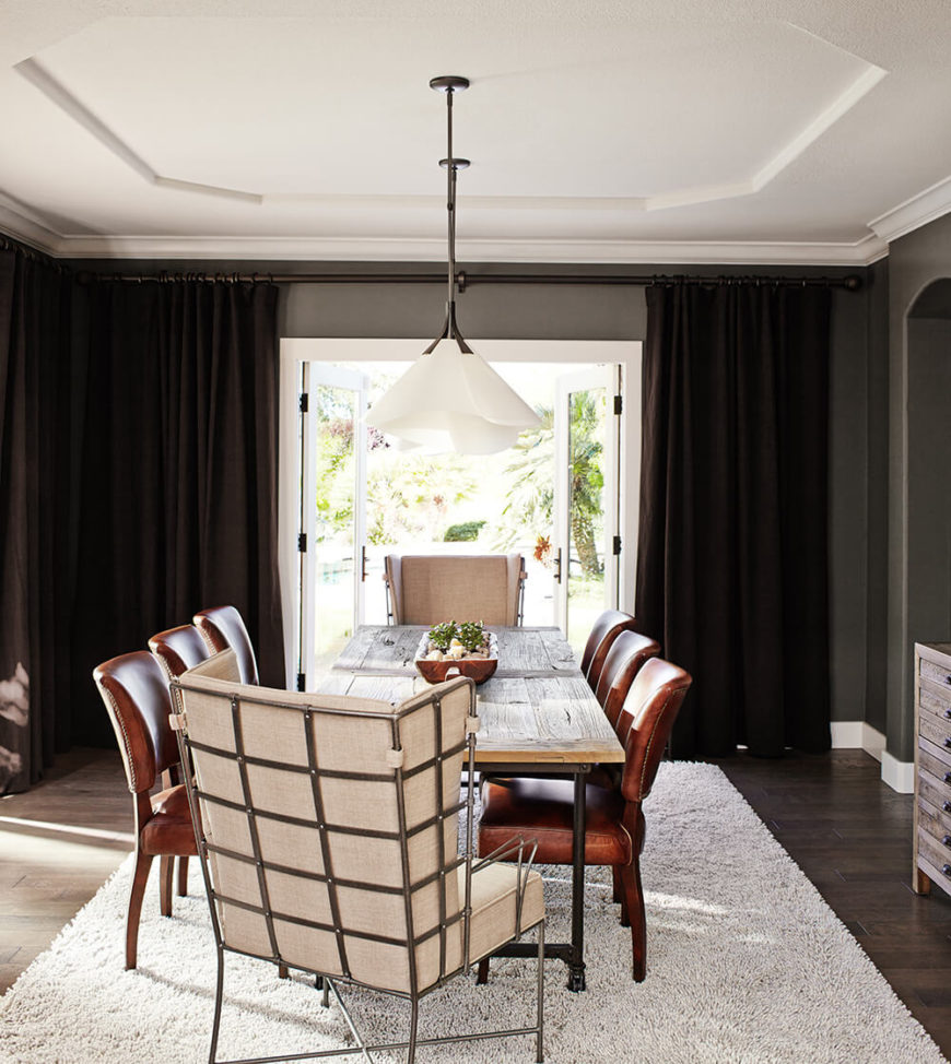 The dining room centers on a unique rustic industrial hybrid table, with black steel frame and aged wood tabletop. This look contrasts with the elegant dark hardwood flooring and nailhead trim leather seating that surrounds the table. The dining room centers on a unique rustic industrial hybrid table, with black steel frame and aged wood tabletop. This look contrasts with the elegant dark hardwood flooring and nailhead trim leather seating that surrounds the table.