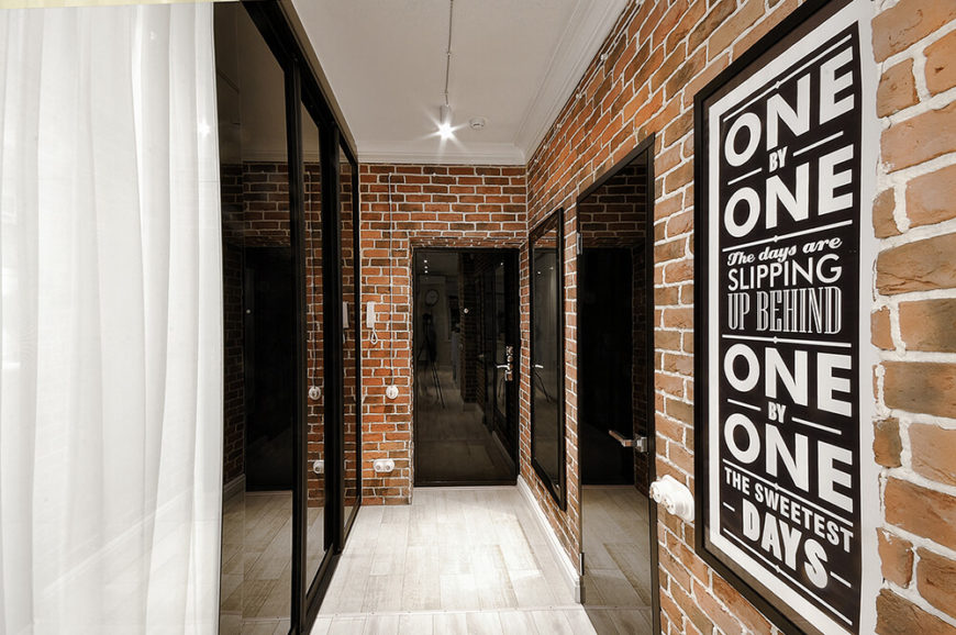As we enter the apartment, we are greeted by a long brick hall with mirrored doors. One door leads to the bathroom, another is a large coat closet and houses the washing machine. The third leads into the main living space. As we enter the apartment, we are greeted by a long brick hall with mirrored doors. One door leads to the bathroom, another is a large coat closet and houses the washing machine. The third leads into the main living space.