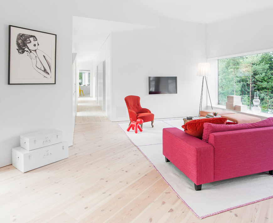 Turning the opposite way, toward the hall connecting the bedrooms, we see a massive full height window to the right, allowing for expansive forest views from the living room. The nearly bleached tone of the hardwood flooring complements the white walls. Turning the opposite way, toward the hall connecting the bedrooms, we see a massive full height window to the right, allowing for expansive forest views from the living room. The nearly bleached tone of the hardwood flooring complements the white walls.