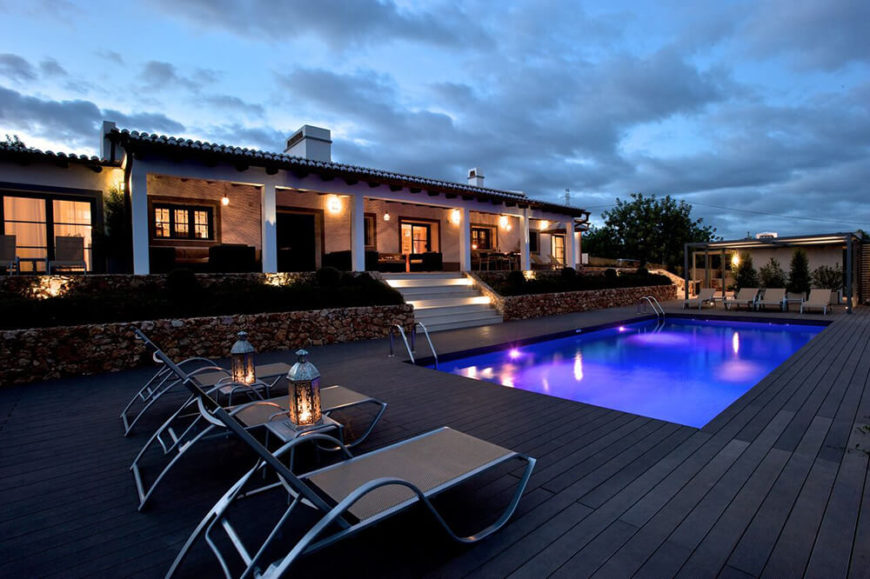 Out back, we see the massive deck sprawling to both ends of the property, with a decent sized pool at center. The dark wood planks match the rich colors of the landscape well. Out back, we see the massive deck sprawling to both ends of the property, with a decent sized pool at center. The dark wood planks match the rich colors of the landscape well.