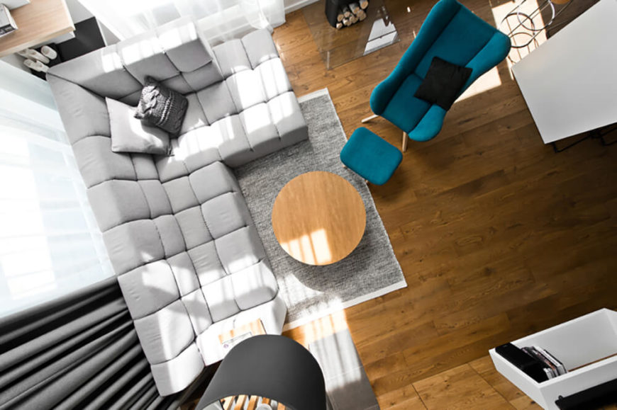 In this overhead view of the living room, we can readily see the balanced arrangement of tasteful furniture, with a neutral set of tones against the rich hardwood flooring. A single blue armchair and ottoman offer a burst of color in this room. In this overhead view of the living room, we can readily see the balanced arrangement of tasteful furniture, with a neutral set of tones against the rich hardwood flooring. A single blue armchair and ottoman offer a burst of color in this room.