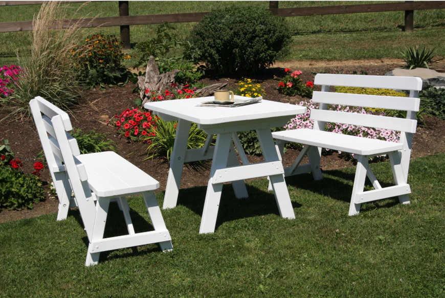 Here is a very small picnic table out by a flower garden. This is a bright and clean choice for a breezy area. White is a color that is often perfect for light and welcoming spaces. 