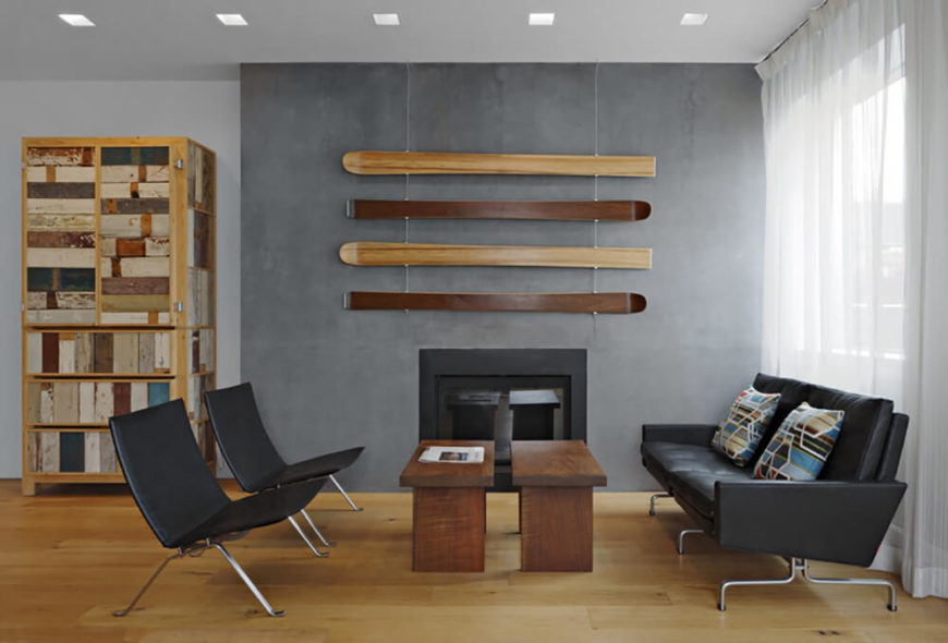 The simple living room area has modern black leather furniture, a gas fireplace, and modular wooden coffee tables. Sheer curtains obscure the view from the outside but still allow plenty of light in to the room. The simple living room area has modern black leather furniture, a gas fireplace, and modular wooden coffee tables. Sheer curtains obscure the view from the outside but still allow plenty of light in to the room.