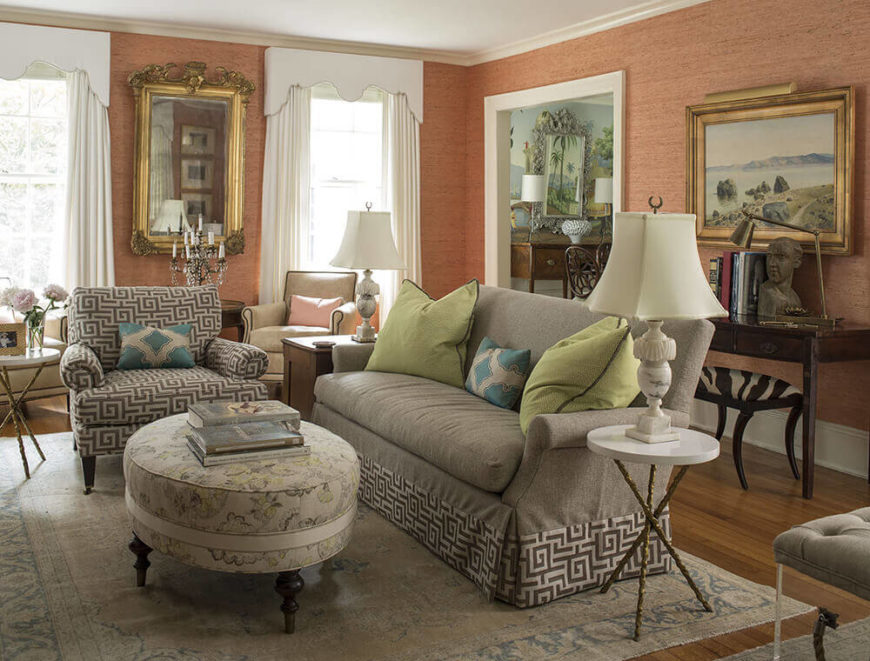 The living room is wrapped in warm salmon tones, with a textural wallpaper finish that helps connect the various artworks and other important details throughout the room. Furniture selection leans toward traditional shapes with modern tones. The living room is wrapped in warm salmon tones, with a textural wallpaper finish that helps connect the various artworks and other important details throughout the room. Furniture selection leans toward traditional shapes with modern tones.