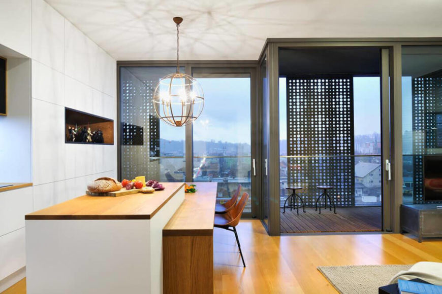 Viewed across the central open space, we see the lengthy kitchen island with plenty of dining space. Here, the full height windows and sliding glass panels reveal the expansive views and the broad balcony. Viewed across the central open space, we see the lengthy kitchen island with plenty of dining space. Here, the full height windows and sliding glass panels reveal the expansive views and the broad balcony.